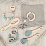 Coffret cadeau de naissance Arthur comprenant attache tétine, couvert, anneau de dentition, peigne et doudou, couleurs beige et vert sauge