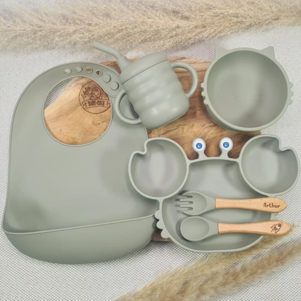 Coffret Naissance en silicone vert comprenant un bavoir, une assiette en forme de crabe, un bol et des couverts