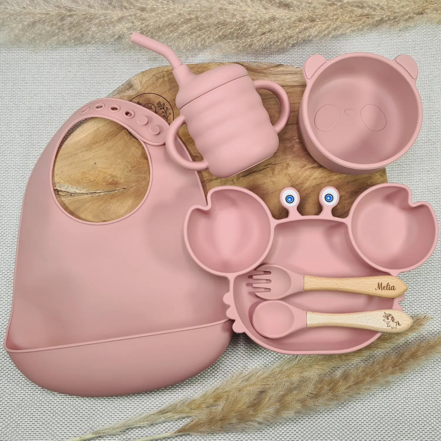 Coffret Naissance en silicone rose incluant un bavoir doux, un bol en forme d'ours et des couverts en bois.